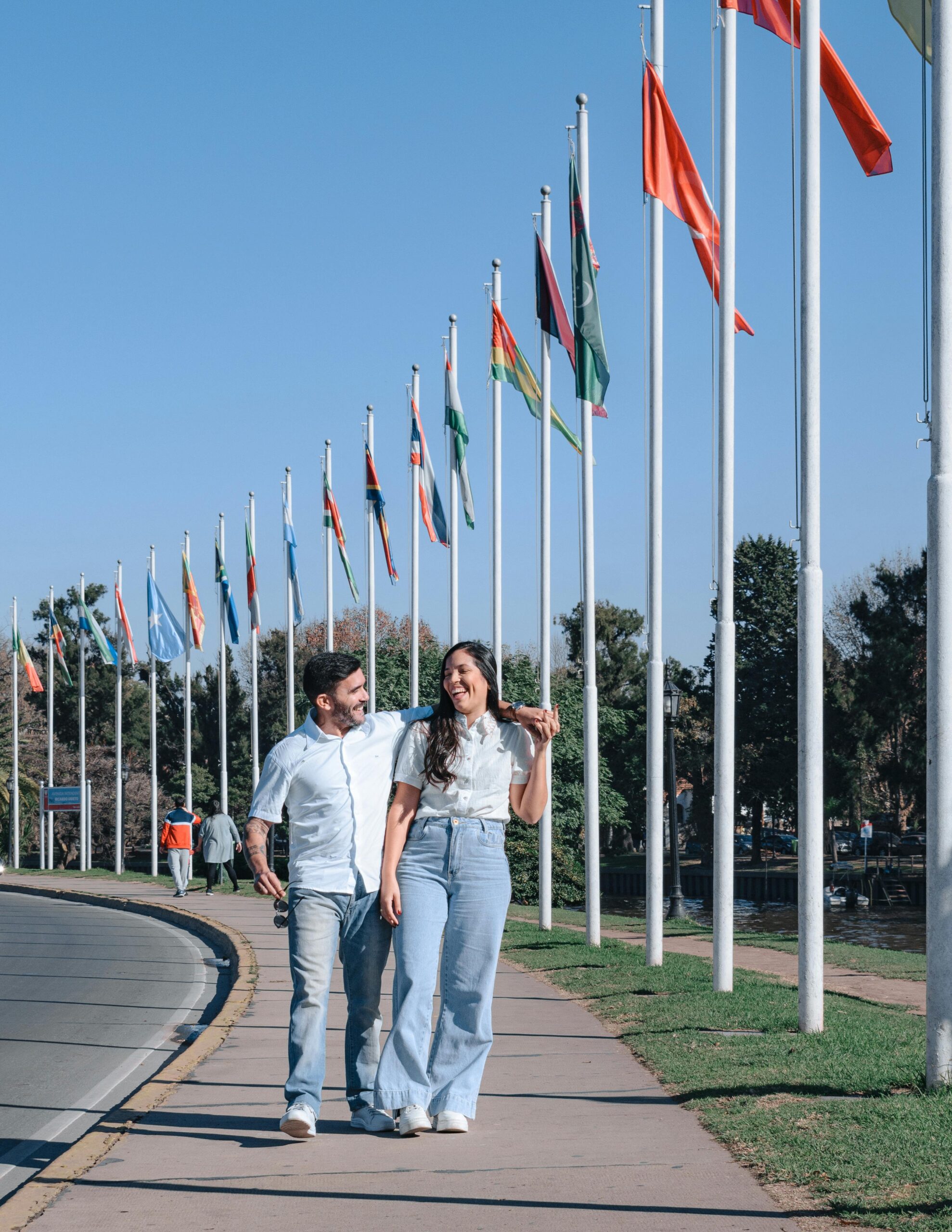 A happy couple enjoys a sunny day, strolling along an avenue lined with flags in Tigre, Argentina.